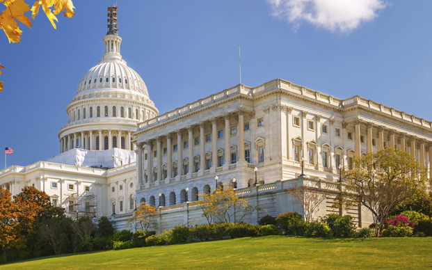 Color photograph of the US Capital Building in the season of Fall, with leaves on trees turning yellow.